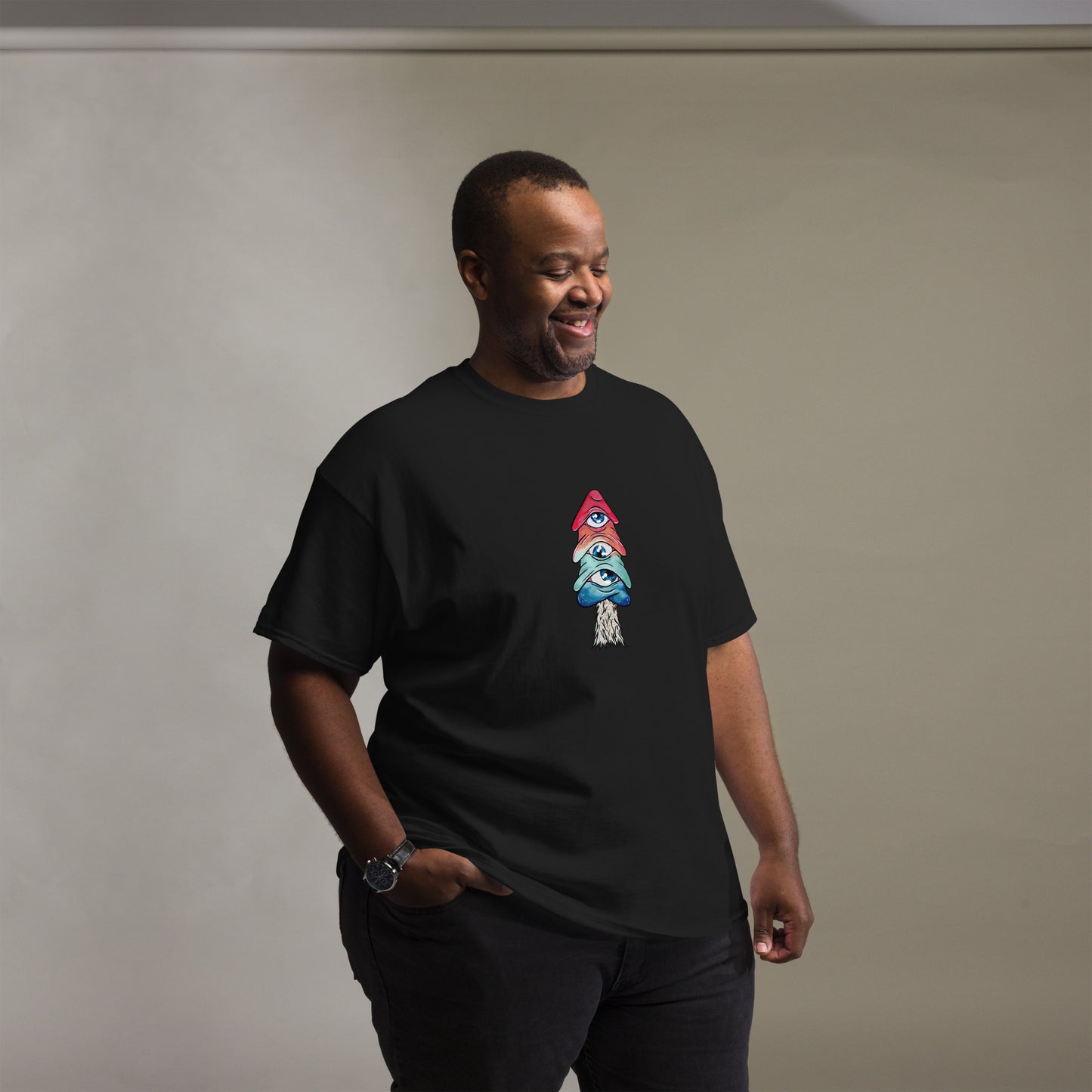 male model wears black crew neck tshirt mushroom with 3 eyes in pink green and blue side view