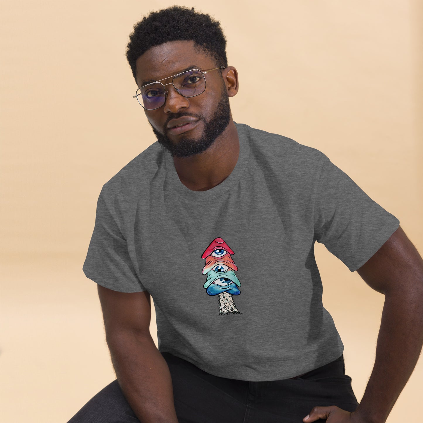 male model wears dark heather crew neck tshirt mushroom with 3 eyes in pink green and blue 