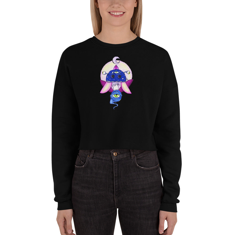 female wears black crop sweatshirt with psychedelic toadstool mushroom with eyes full moon crescent moon flying insect design in winter blue and purple