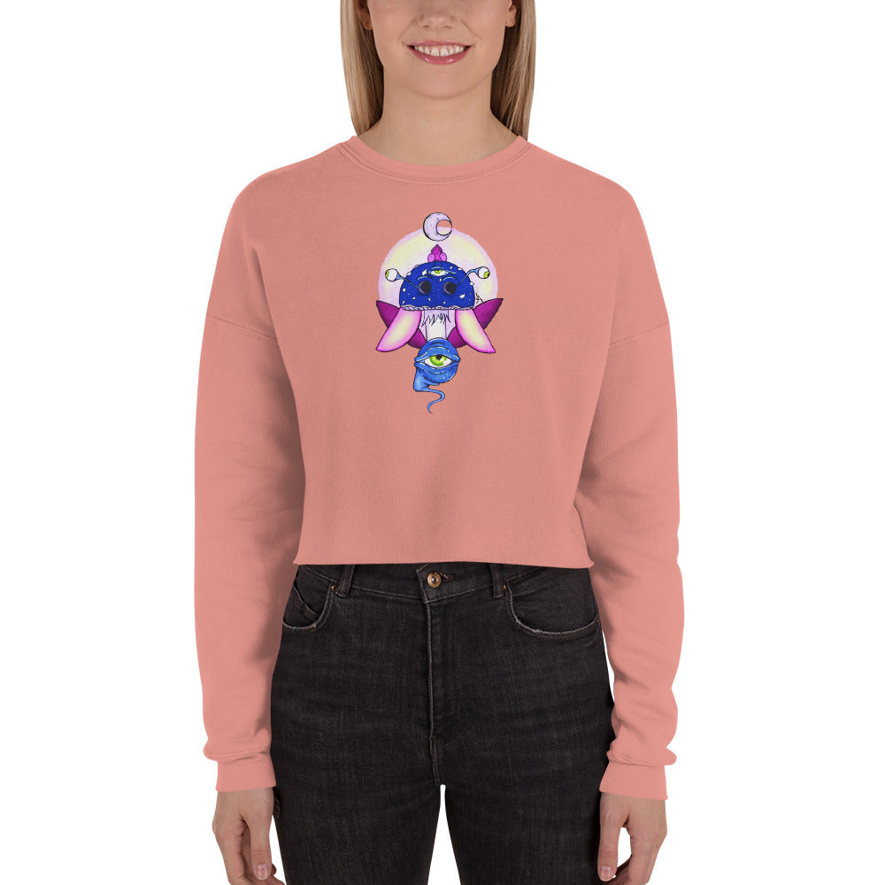 female wears mauve crop sweatshirt with psychedelic toadstool mushroom with eyes full moon crescent moon flying insect design in winter blue and purple